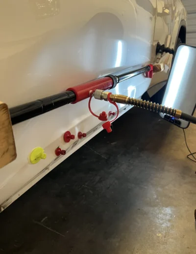 Glue-pull paintless dent repair tools on a white car door
