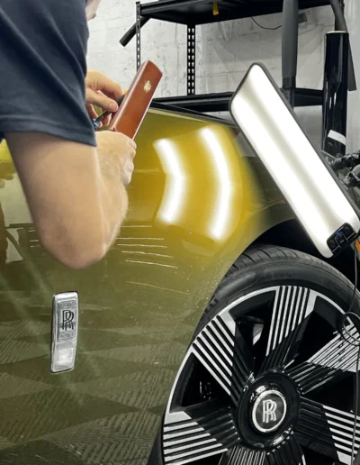 PDR technician removing a dent on a Rolls-Royce with an LED reflection board