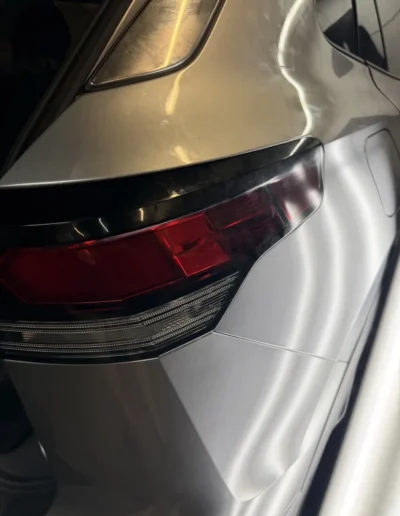 Silver SUV rear quarter panel after paintless dent repair, checked under an LED board